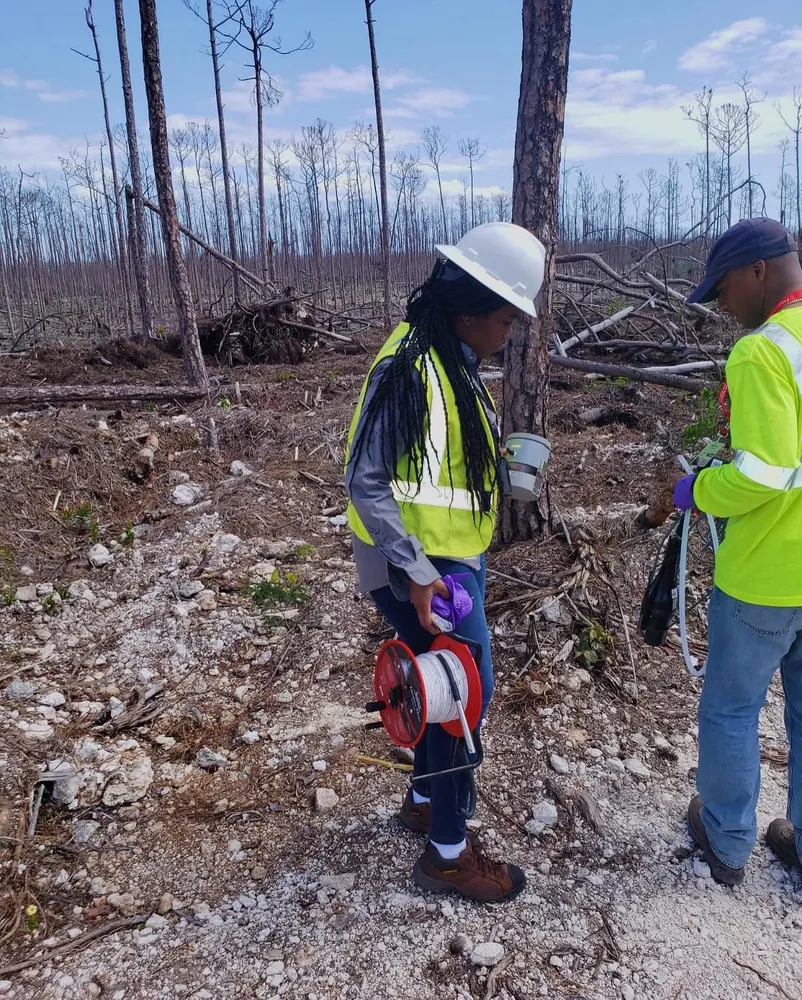 Kariel in a hard hat among burned pines on Grand Bahama