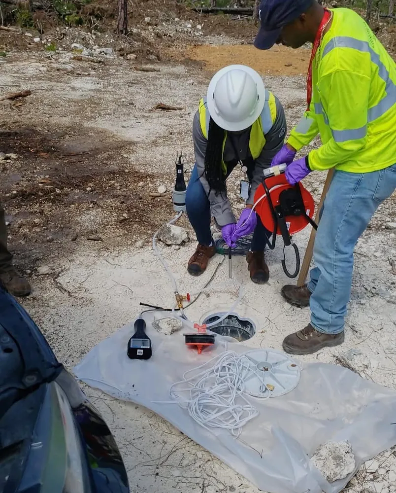 Kariel in a hard hat sampling groundwater after Hurricane Dorian
