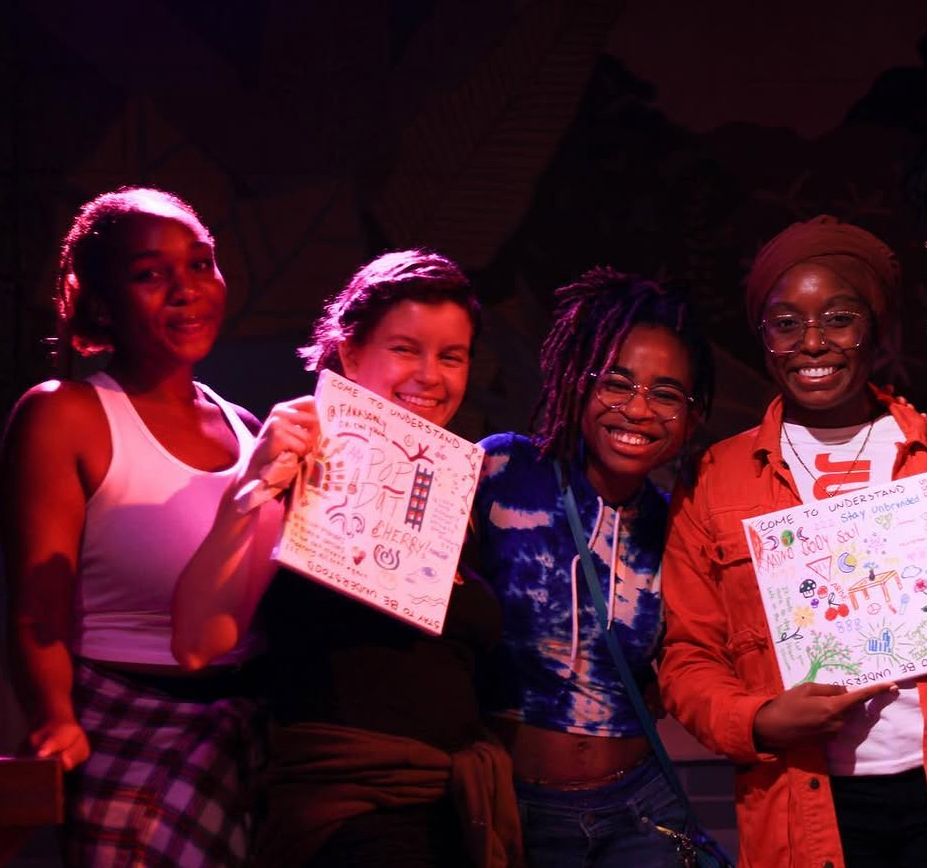 Kariel with participants holding artwork at a DOPENMIC event